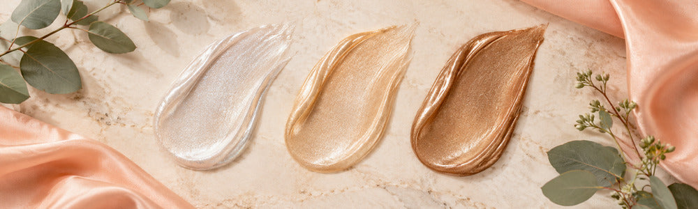 Diamond, gold and bronze shimmer lotion swatches on warm stone