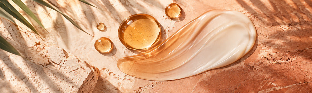 Amber sunless-tanning droplets blended into lotion on warm stone