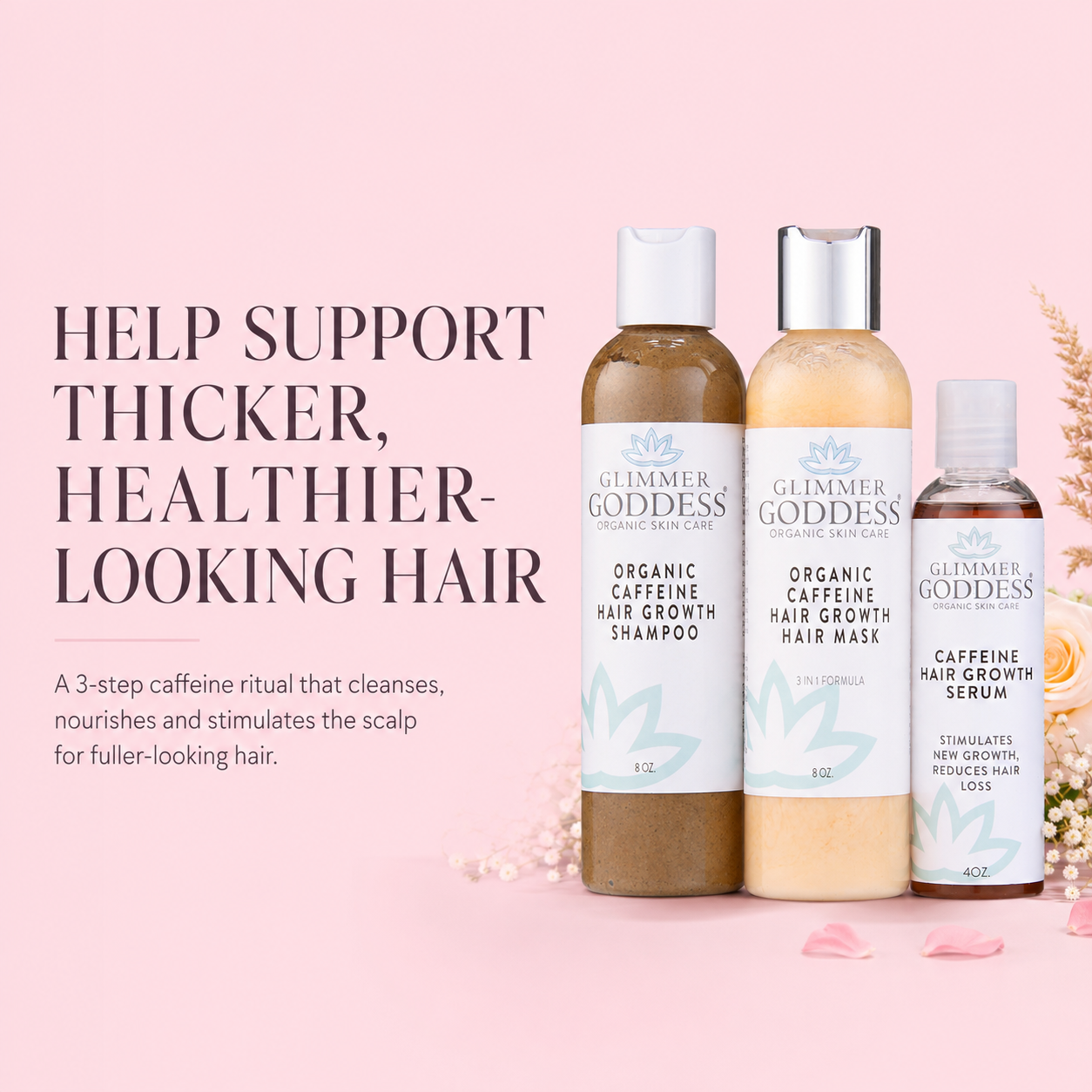 Three Glimmer Goddess hair care bottles arranged on a soft pink background with decorative dried flowers. The products include Organic Caffeine Hair Growth Shampoo, Organic Caffeine Hair Growth Mask, and Caffeine Hair Growth Serum.