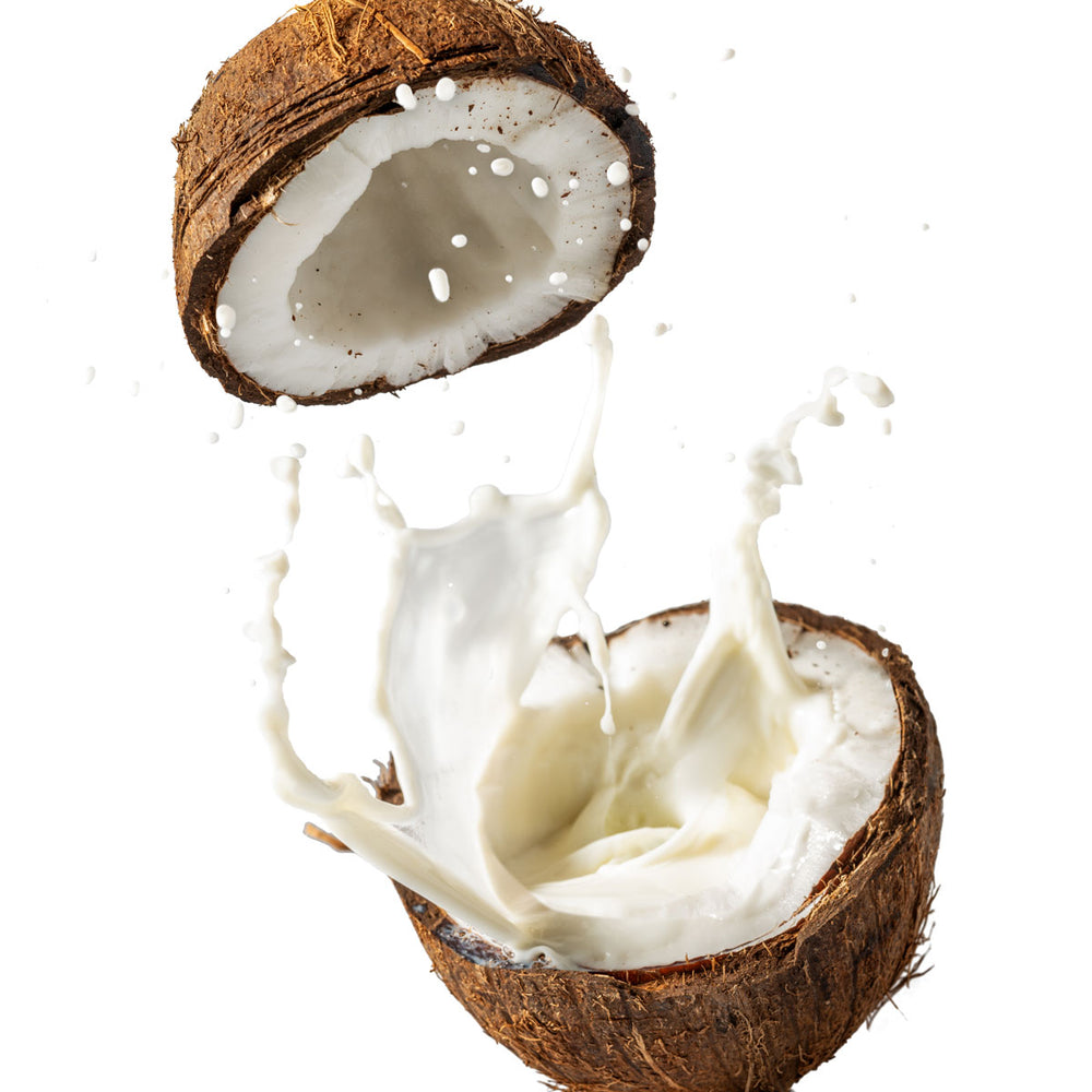 Fresh coconut halves with coconut milk splashing, used in organic skin care products