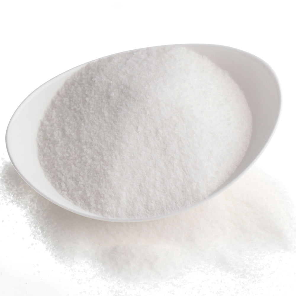 Bowl of fine white salt, a common skincare ingredient, on a white background.